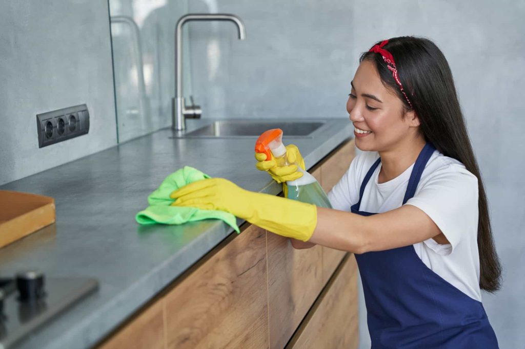 en asiatisk kvinna torkar rent arbetsbänk i kök